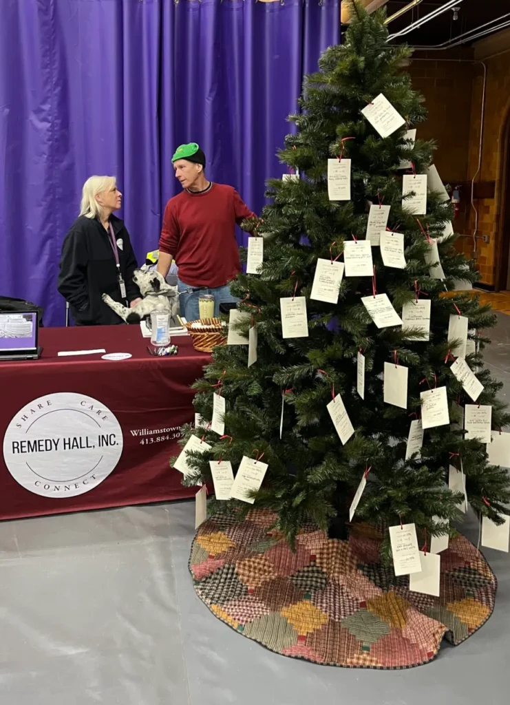 Remedy Hall Board members Andi and Dan Bryant with their dog Rugby (honorary board member) at the Non-Profit Fair, December 2024.Remedy Hall Board members Andi and Dan Bryant with their dog Rugby (honorary board member) at the Non-Profit Fair, December 2024.